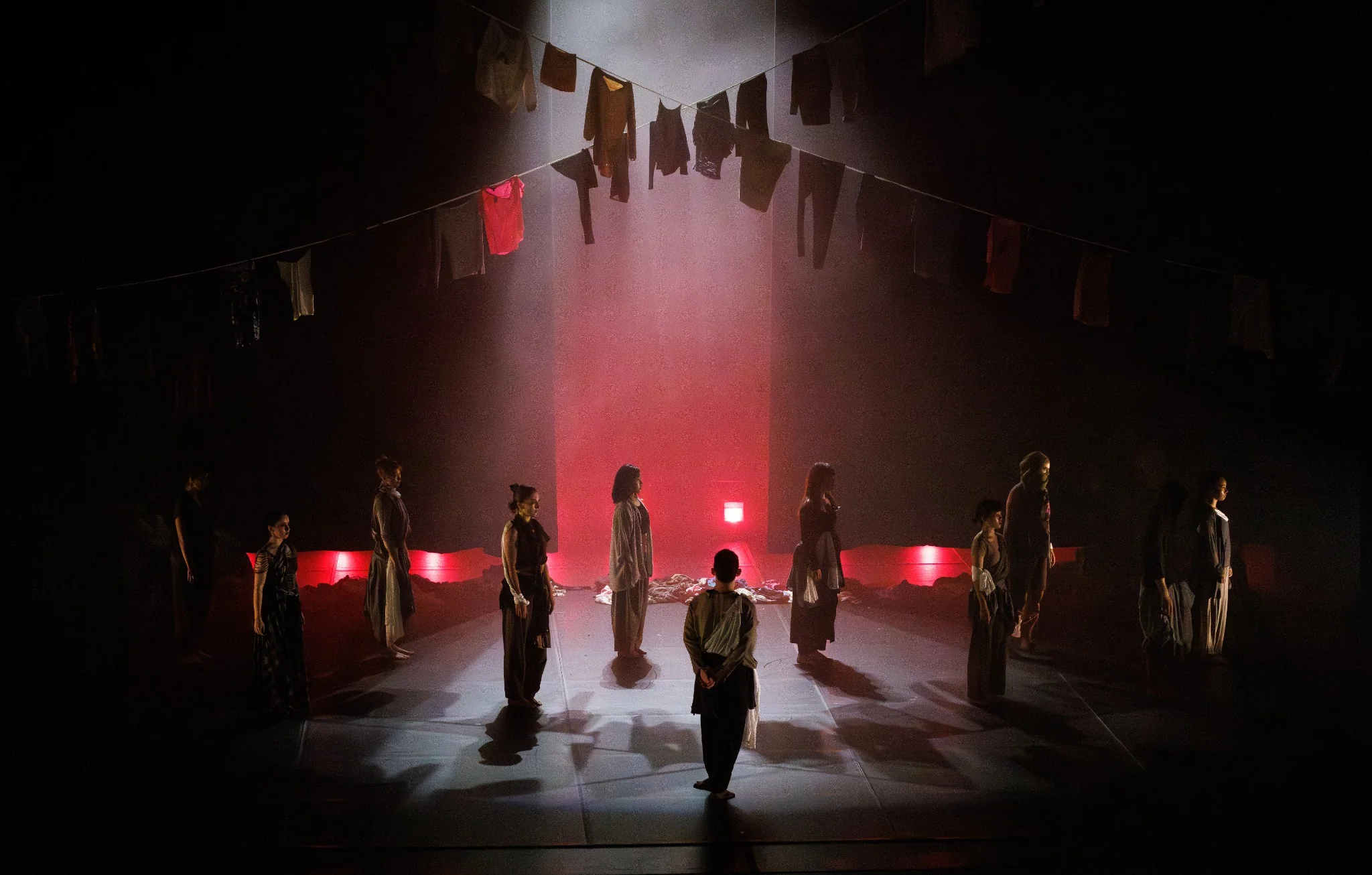 Future Traces ensemble beneath suspended garments and red stage lighting